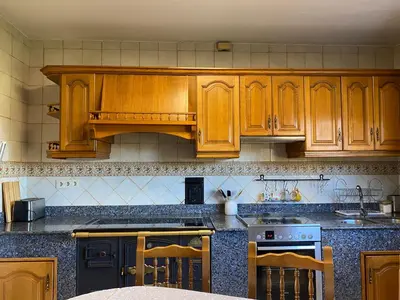 a kitchen with wooden cabinets and a stove at Casa Rosiña in Campo Lameiro