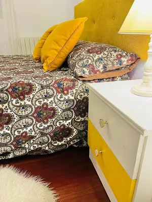 a bed with two pillows and a table with a lamp at Tineo centro in Tineo