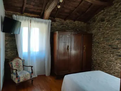 a bedroom with a bed and a cabinet and a chair at Rural Milia Arzúa - Transporte gratuíto desde la ciudad o conexión directa a pie desde el Camino in Arzúa