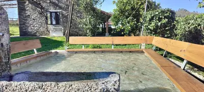 a wooden bench sitting next to a tree at Rural Milia Arzúa - Transporte gratuíto desde la ciudad o conexión directa a pie desde el Camino in Arzúa