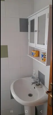 a bathroom with a white sink and a white cabinet at Casa da Tita