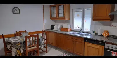 a kitchen with wooden cabinets and a sink and a table at Casa da Tita