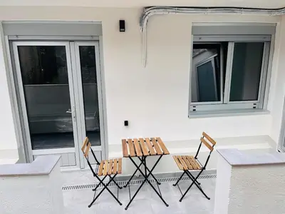 two chairs and a table on a porch with two windows at Valdeflores Flats Bj in Viveiro