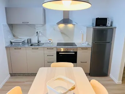 a kitchen with a table and a sink and a refrigerator at Valdeflores Flats Bj in Viveiro