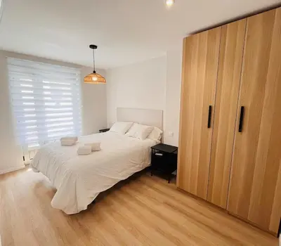 a bedroom with a large bed and a large wooden cabinet at Valdeflores Flats Bj in Viveiro
