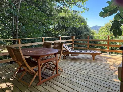 a wooden deck with a table and chairs and a bench at Vivienda turística en plena naturaleza O Poleiro