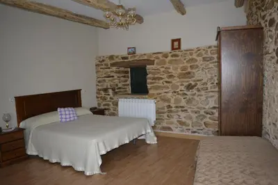 a bedroom with two beds and a stone wall at La Casa de Rosa in Filiel