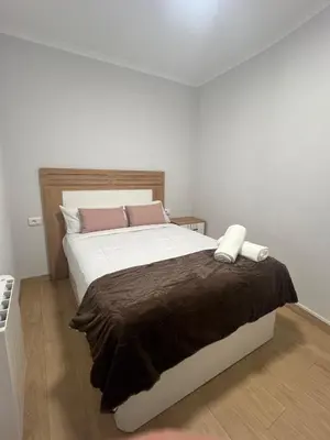 a bedroom with a large white bed with brown blanket at Casco histórico Allariz-Iria in Allariz