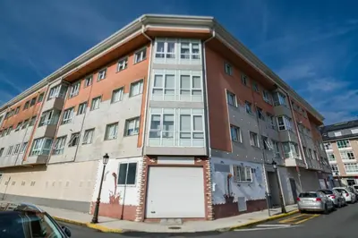 a building on a street with cars parked in front of it at Mirador del Tambre Etapa final del Camino in Sigüeiro