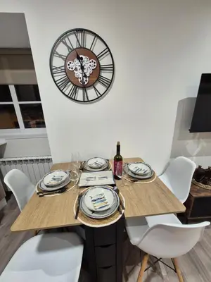 a dining room table with a clock on the wall at Escola in Ourense