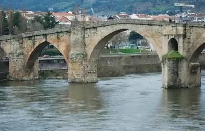 a stone bridge over a river in a city at Escola in Ourense