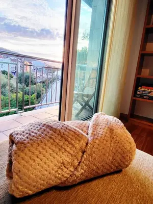 a blanket sitting on a bed in front of a window at O lar da luz in Ourense