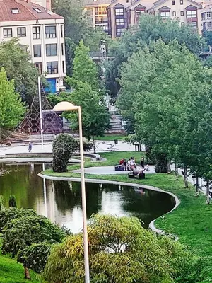 a park with a pond and people sitting on benches at O lar da luz in Ourense