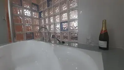 a bottle of wine sitting next to a bath tub at Ameli House By PECA in Silleda