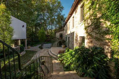 a stone building with a staircase next to a house at Hotel Sarela Natura in Santiago de Compostela