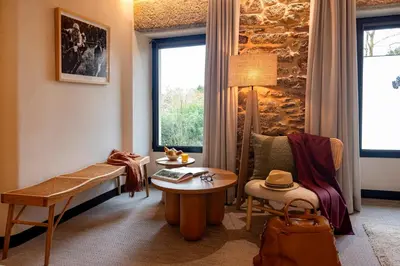 a room with a bench and a table and a window at Hotel Sarela Natura in Santiago de Compostela