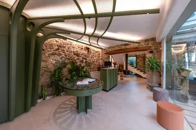 a lobby with a table and a stone wall at Hotel Sarela Natura in Santiago de Compostela