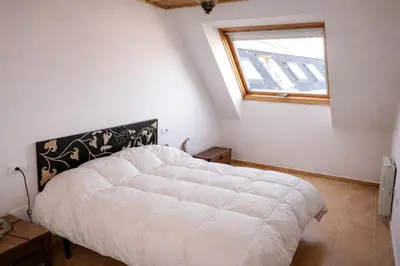 a white bed in a room with a window at Winahost Ático Viveiro in Viveiro