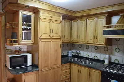 a kitchen with wooden cabinets and a microwave at Chuca House in Requiás