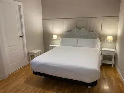 a bedroom with a large white bed with two lamps at Pensión Camino del Sil in Sobradelo