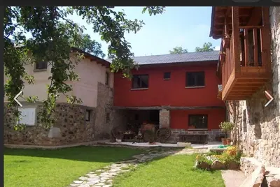 a red and white house with a grass yard at Mirador de Babia II in Ríolago