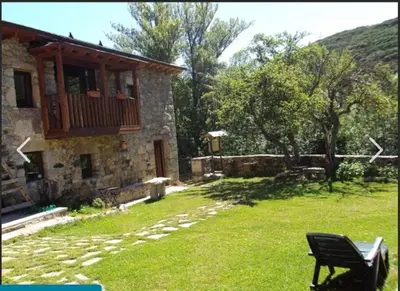 a stone house with a bench in a yard at Mirador de Babia II in Ríolago