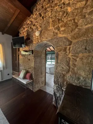 a room with a stone wall with a couch and a tv at Aldea Figueiredo in San Amaro