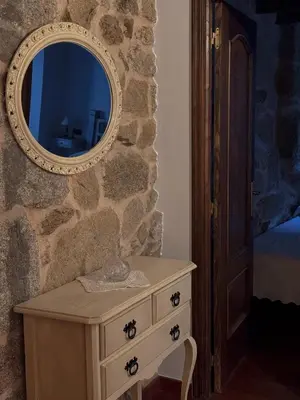 a dresser with a mirror on a stone wall at Aldea Figueiredo in San Amaro