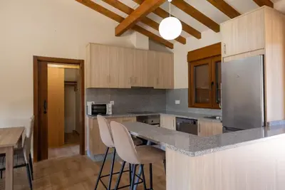 a kitchen with a counter with chairs and a refrigerator at YourHouse Casa Canastro in Allariz