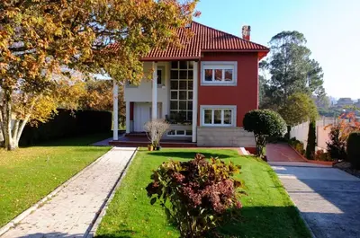 a red house with a green lawn in front of it at Casa D Aitana in Pardaces de Arriba