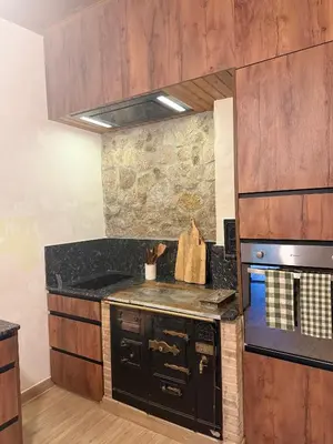 a kitchen with a black stove top oven next to a stone wall at O Caliu das Airas in León