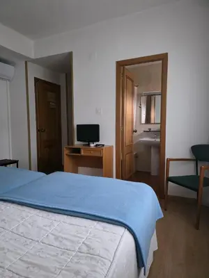 a bedroom with a bed and a desk with a television at Hotel Espada in A Rua
