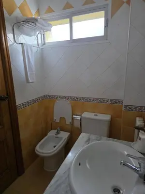 a bathroom with a sink and a toilet and a window at Hotel Espada in A Rua