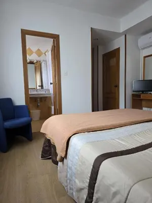 a bedroom with a large bed and a blue chair at Hotel Espada in A Rua