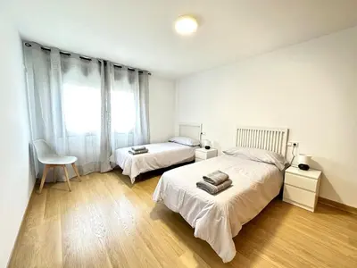 a bedroom with two beds and a chair and a window at Alice House in Miño