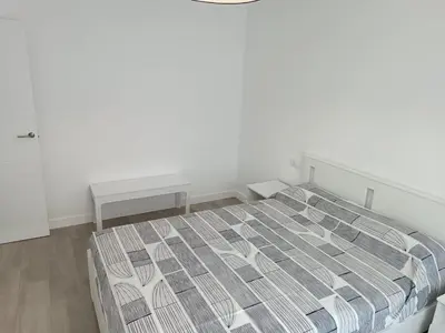 a white bedroom with a bed and a table at Vivienda Ares Centro in Ares