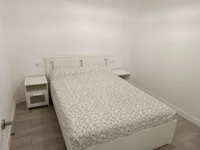 a white bed in a white room with two tables at Vivienda Ares Centro in Ares