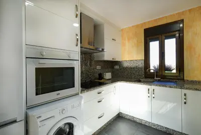 a kitchen with white cabinets and a washer at YourHouse Casa Antonio in Amoeiro