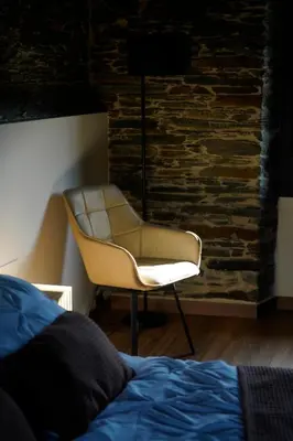 a bedroom with a chair next to a brick wall at Casa Rural Lugar Vista Alegre in Lugo