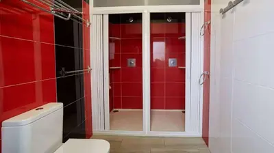 a red bathroom with a toilet and a shower at Albergue Ezequiel in Melide