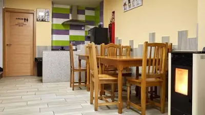 a dining room with a table and chairs and a kitchen at Albergue Ezequiel in Melide