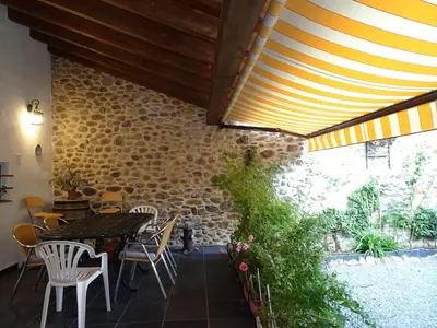 a patio with a table and chairs and a brick wall at A CASONA DO BARCO con garaje privado, jardín y buenas vistas in O Barco de Valdeorras