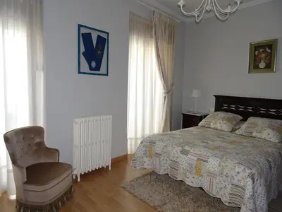 a bedroom with a bed and a chair and windows at A CASONA DO BARCO con garaje privado, jardín y buenas vistas in O Barco de Valdeorras