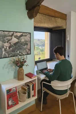 a man sitting at a desk with a laptop computer at Holiday Home Galicia Retreat by Interhome in Cerdedo