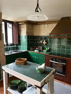 a kitchen with green cabinets and a table with plates at Casa de la fuente de Vista Alegre in Sarria