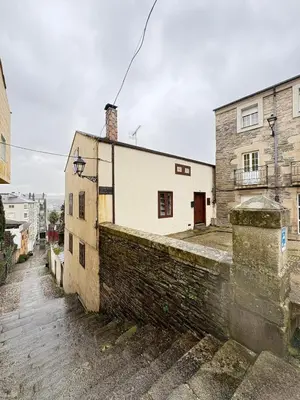 a building with a brick wall next to a street at Casa de la fuente de Vista Alegre in Sarria