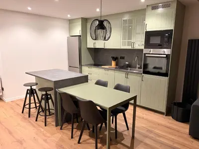 a kitchen with white cabinets and a table and chairs at Milagrosa Square in Lugo