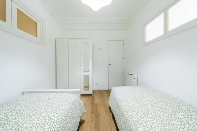 two beds in a bedroom with white walls and windows at Apartamento dentro de la Muralla de Lugo, Rúa Nova in Lugo