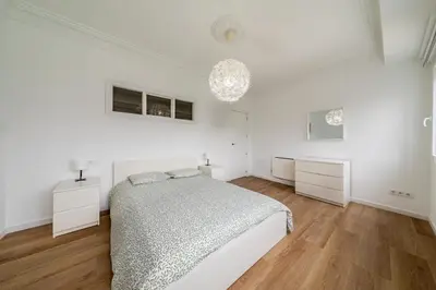 a white bedroom with a bed and a chandelier at Apartamento dentro de la Muralla de Lugo, Rúa Nova in Lugo