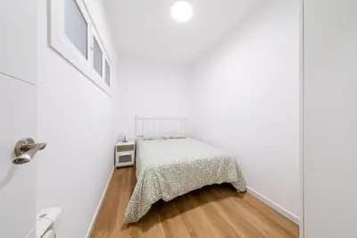 a white bedroom with a bed and a wooden floor at Apartamento dentro de la Muralla de Lugo, Rúa Nova in Lugo